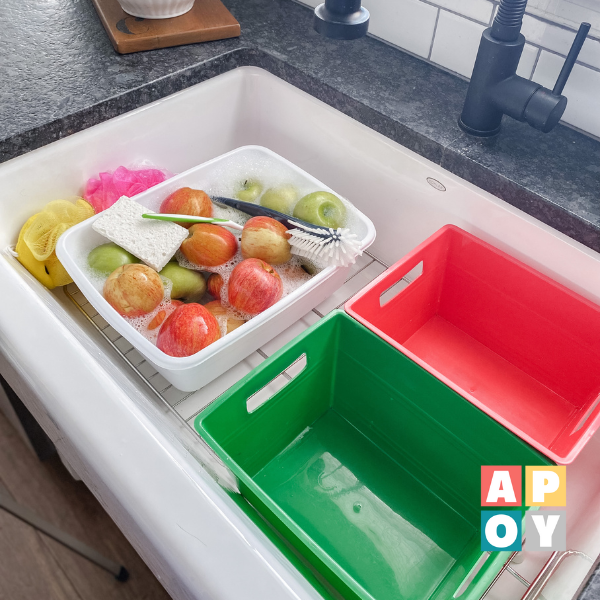 apples in soapy water and colored bins in sink