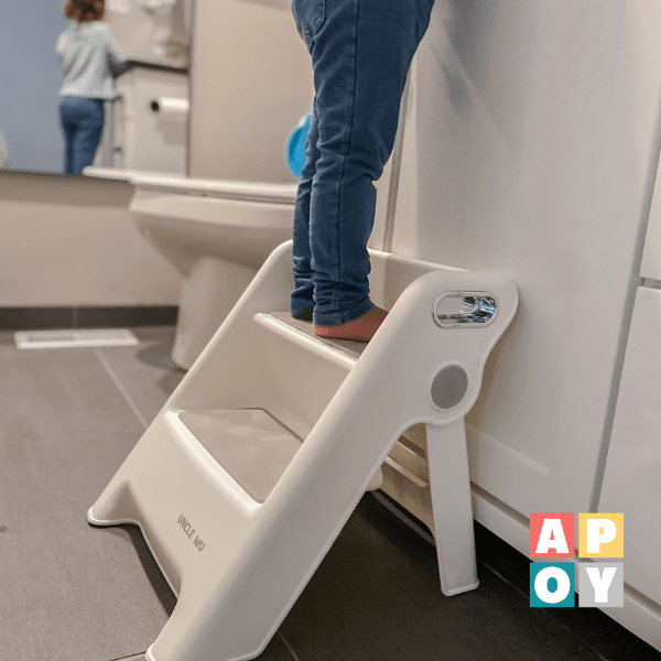 child standing on white two step stool in the bathroom