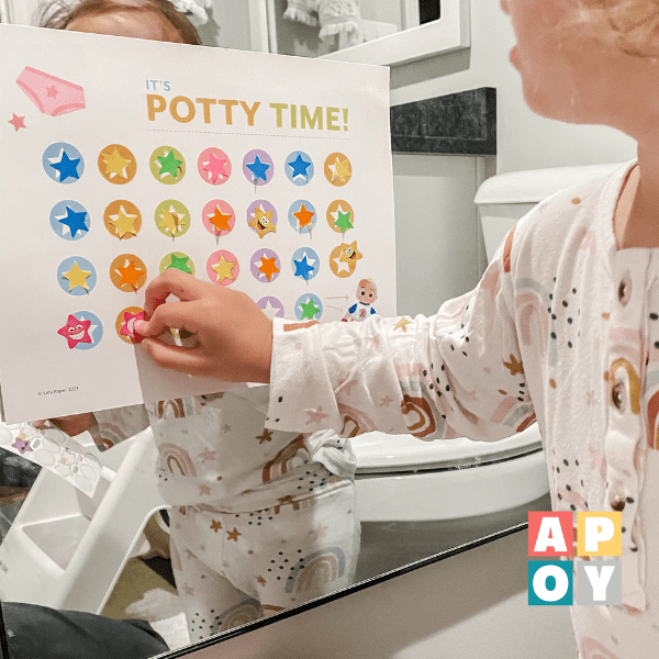 childs hand putting sticker on potty training chart in bathroom