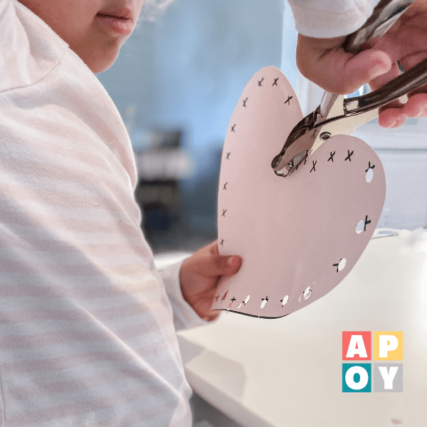 childs hand using hole punch around heart