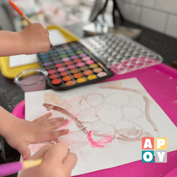 childs hands painting with watercolors on counter