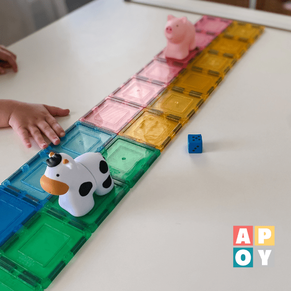 colorful magnetic tiles on table with dice and farm animal toys
