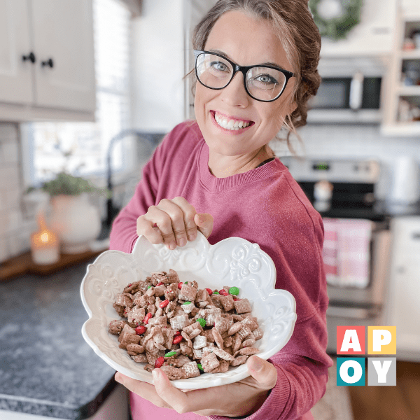 woman holding bowl of christmas puppy chow in kitchen