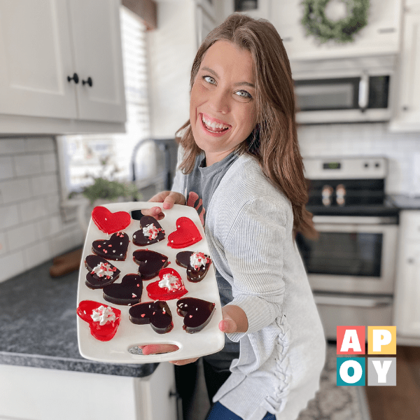 woman holding tray of heart shaped jello jigglers in kitchen