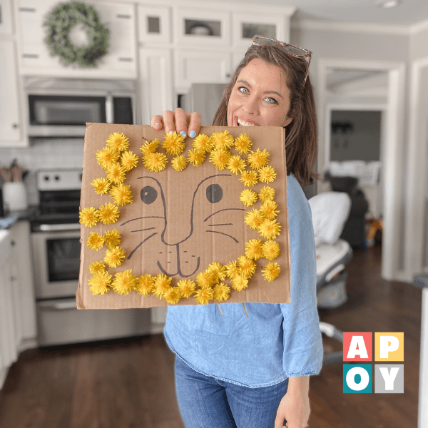woman standing in kitchen holding cardboard lion with dandelion mane
